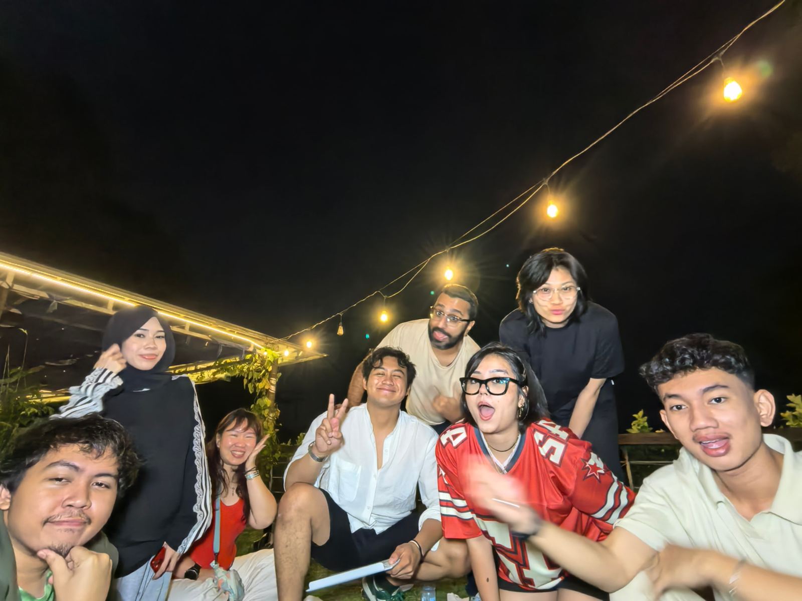 Group photo at night, peace signs everywhere